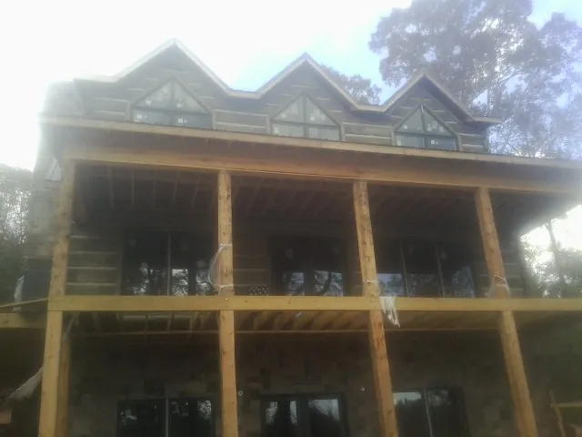 Dormers and porch framing on a large log home under construction — Roof Coating work by our crew in Alamo
