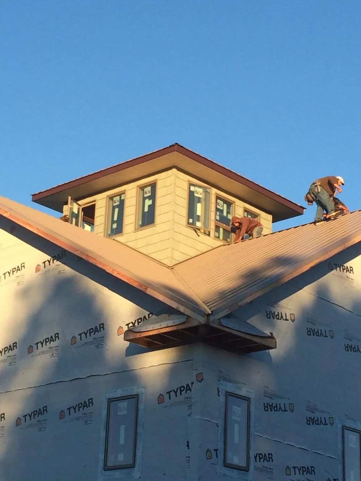 Roofers working around a rooftop cupola on a new metal roof at sunset — Roof Waterproofing in Alamo by Roofing Brothers